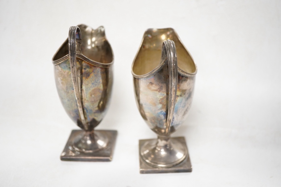 A George III silver helmet shaped cream jug, London, 1795, height 15cm, weighted, together with a later similar cream jug, Birmingham, 1962.